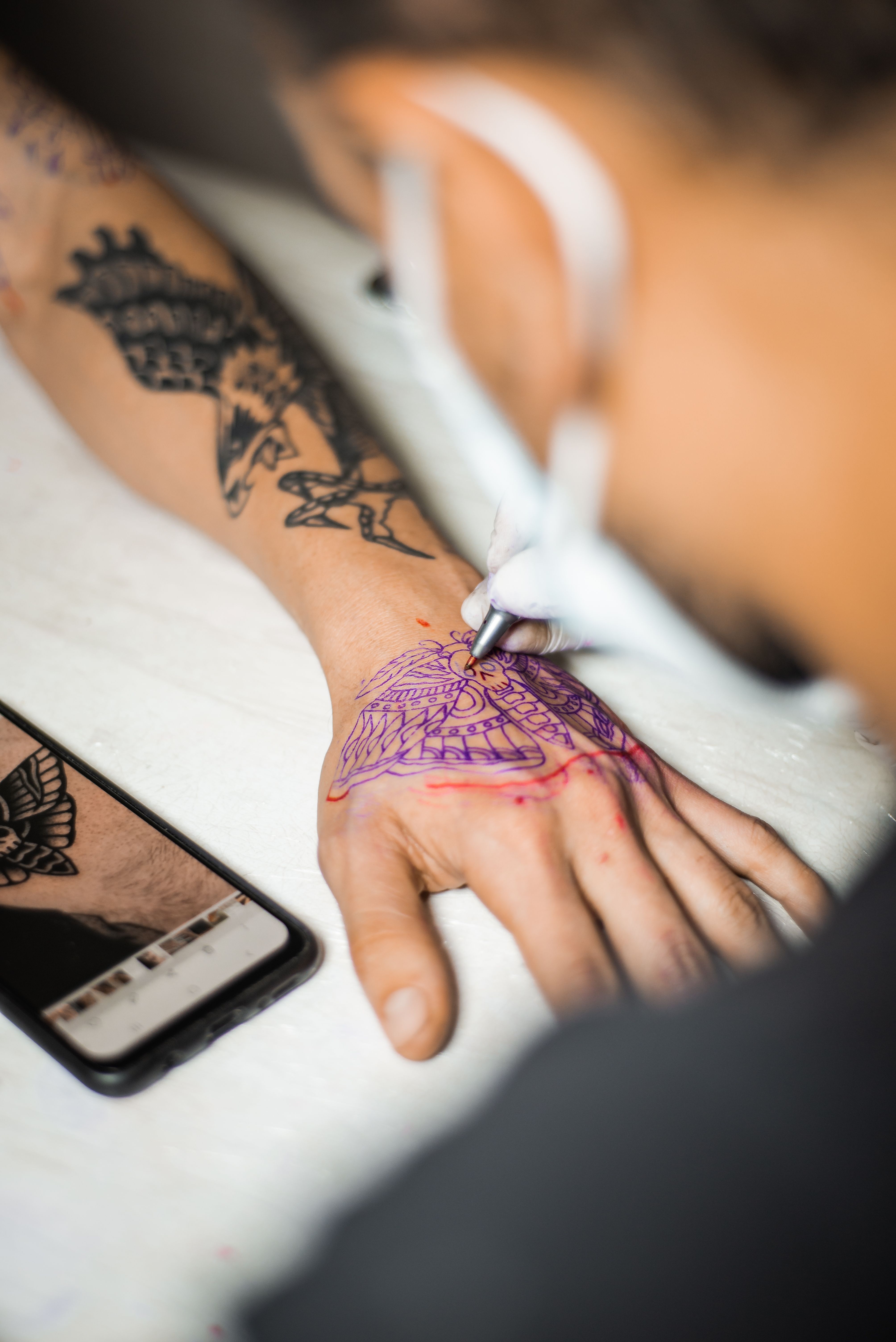 Tatuador aplicando stencil de borboleta na mão da cliente